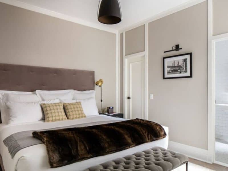 Cozy hotel room at HGU New York featuring a plush bed with decorative pillows, modern lighting, and stylish decor, emphasizing luxury and comfort for guests.