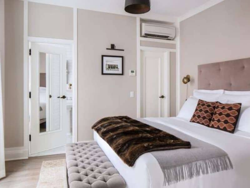 Cozy hotel room at HGU New York featuring a plush bed with decorative pillows, stylish furnishings, and modern amenities, emphasizing comfort and luxury for guests.
