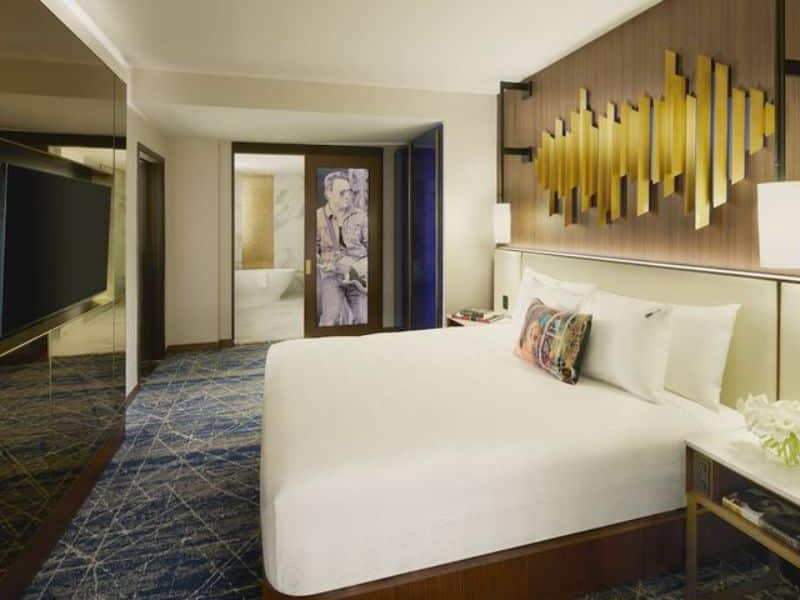 Stylish hotel room at Hard Rock Hotel New York featuring a king-size bed, modern decor, and en suite bathroom access, reflecting luxury accommodations in the Theater District.