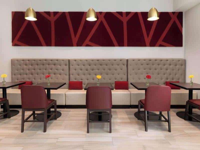 Stylish dining area at Hilton Garden Inn Long Island City featuring tufted seating, tables with floral centerpieces, and modern decor.