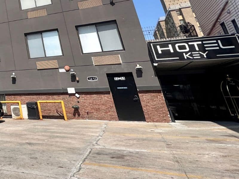 Hotel Key entrance in Flushing, NY, featuring modern signage, parking area, and building facade with large windows.