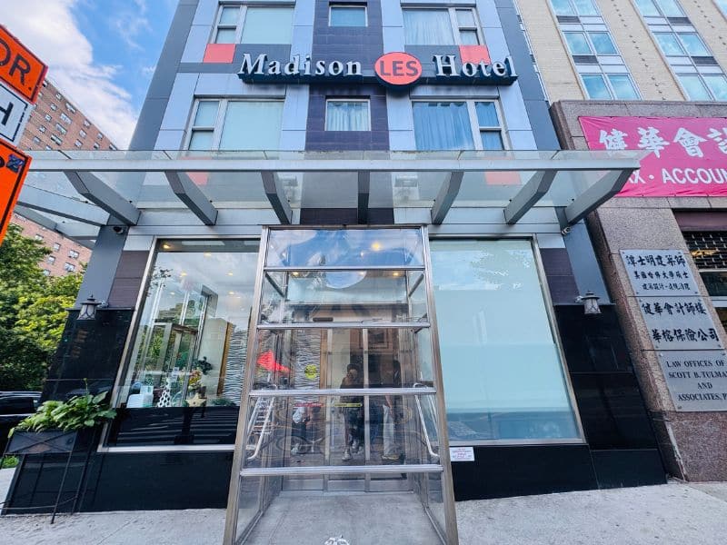 Madison LES Hotel entrance featuring modern architecture, clear signage, and a welcoming atmosphere, located near Chinatown and offering amenities like a rooftop bar and fitness center.