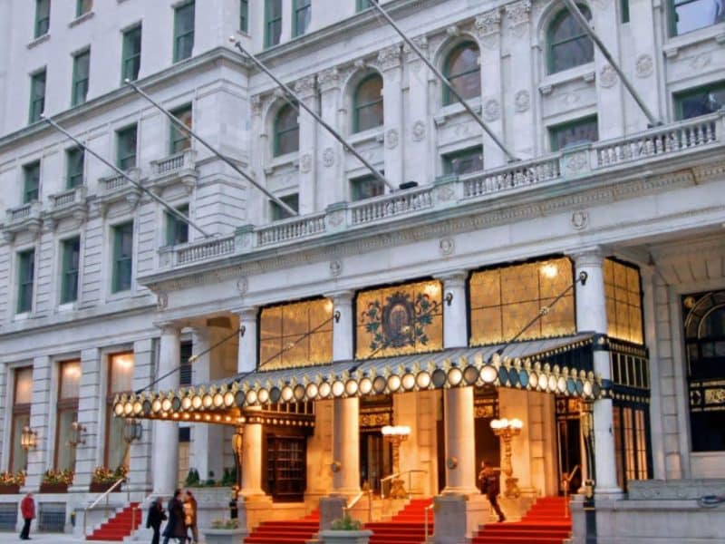 Midtown Manhattan hotel entrance with elegant architecture, illuminated awning, and red carpet, showcasing the vibrant atmosphere of New York City.