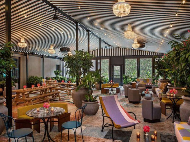 Stylish indoor lounge area at Moxy Brooklyn Williamsburg featuring vibrant decor, seating arrangements, plants, and ambient lighting, ideal for relaxation and socializing.