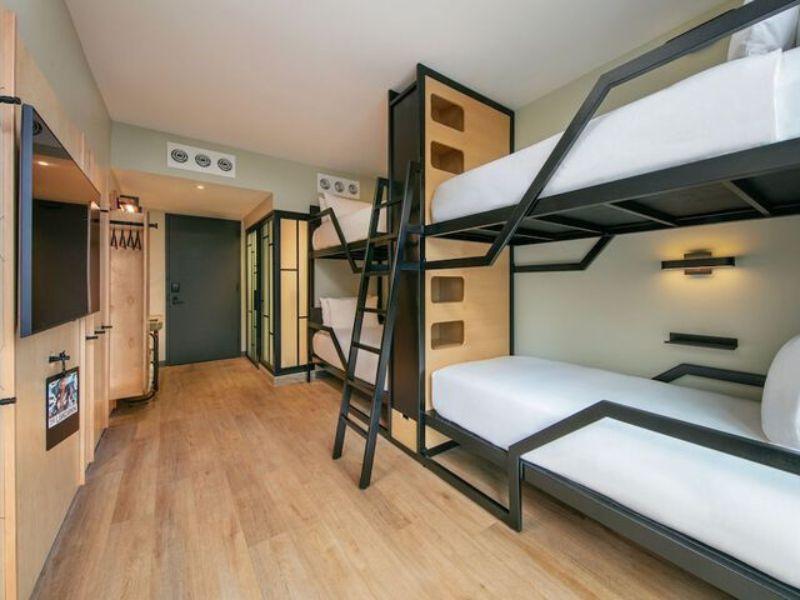Bunk bed room at Moxy Brooklyn Williamsburg hotel featuring stylish decor, wooden flooring, and modern amenities.