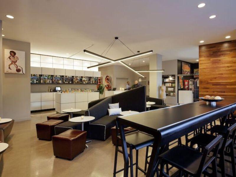 Stylish lounge area of NU Hotel Brooklyn featuring modern seating, a bar with various beverages, and contemporary decor, ideal for relaxation and socializing.