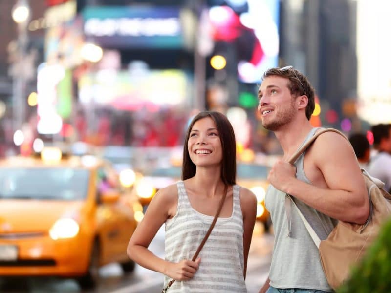 Couple enjoying the vibrant atmosphere of Times Square, NYC, with yellow taxis and bright billboards in the background, reflecting the excitement of a private car tour to The Godfather filming locations.