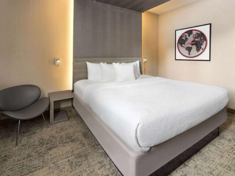 Cozy hotel room at Ramada by Wyndham Bronx featuring a queen bed, modern decor, flat-screen TV, and seating area.