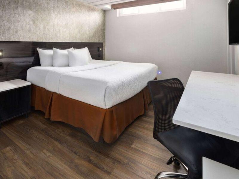 Cozy hotel room at Ramada by Wyndham Bronx featuring a queen bed, desk, and modern decor, emphasizing comfort and convenience for travelers.