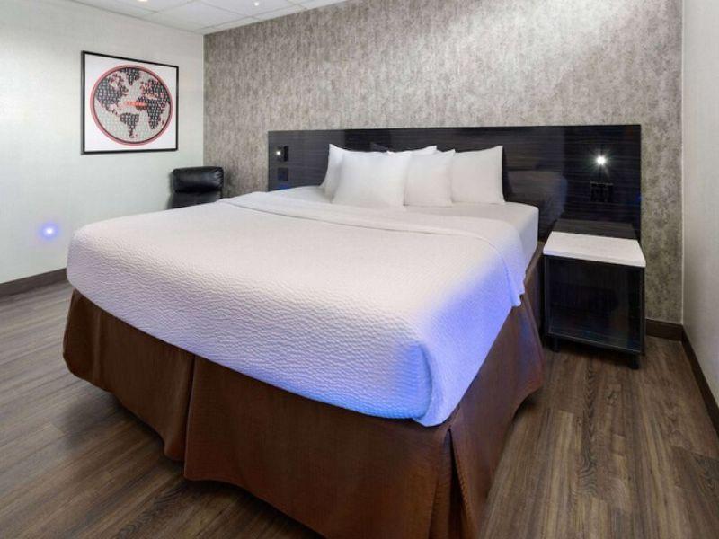Cozy hotel room at Ramada by Wyndham Bronx featuring a large bed, modern decor, and a comfortable seating area, emphasizing amenities for travelers.