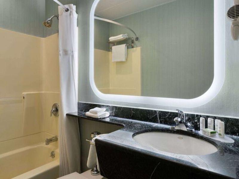Bathroom featuring a bathtub, modern sink with marble countertop, and complimentary toiletries, highlighting amenities at Ramada by Wyndham Bronx.
