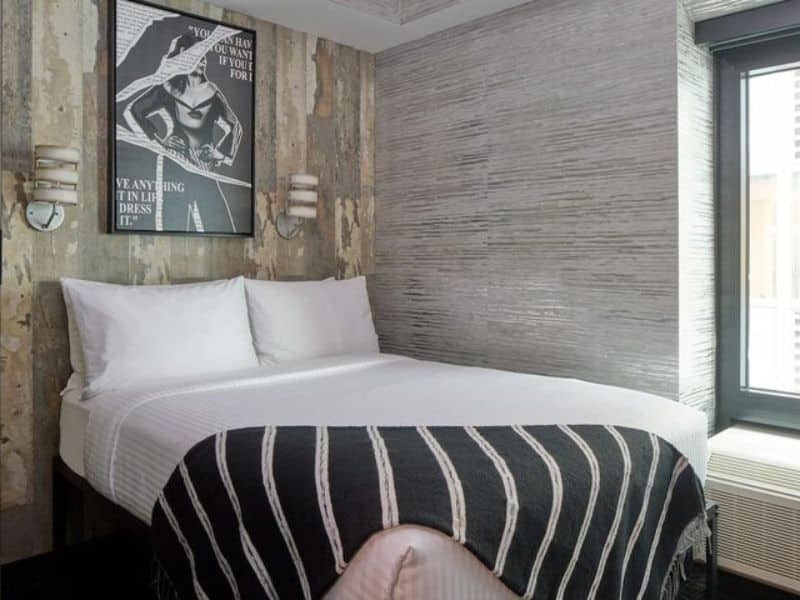Stylish guest room in The FIDI Hotel featuring modern decor, chic lighting, bold artwork, and a cozy bed with plush linens.