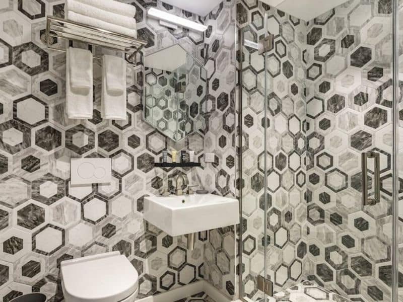 Stylish hotel bathroom featuring modern hexagonal tile design, sleek sink, and contemporary fixtures at The FIDI Hotel in Manhattan.