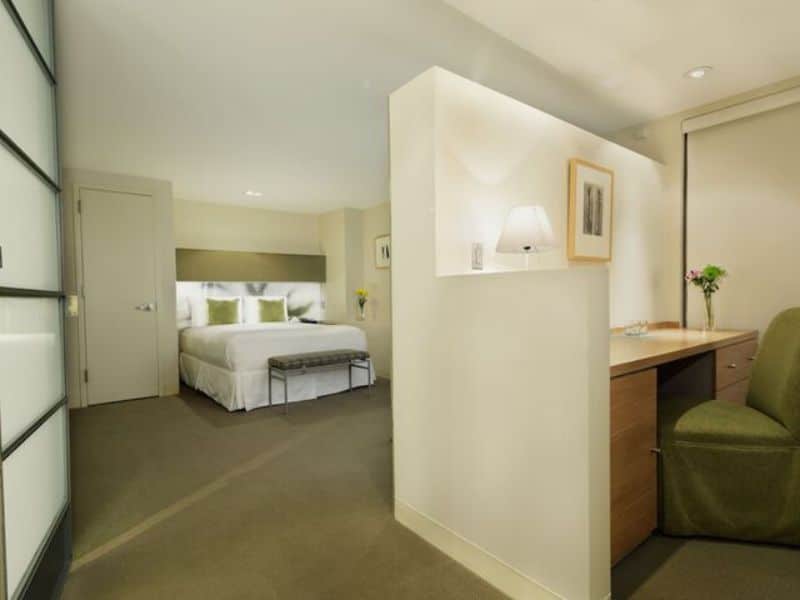 Stylish hotel room at The Shoreham Hotel featuring a queen bed, minimalist decor, desk area, and natural light.
