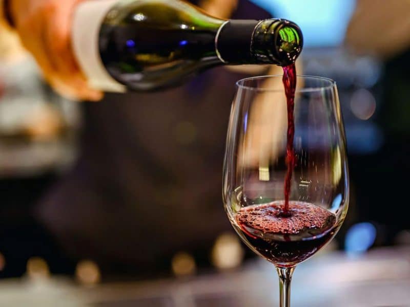 Pouring red wine into a glass, showcasing the wine tasting experience during the Vintage Wine Tasting and Classic Car Combo Tour.