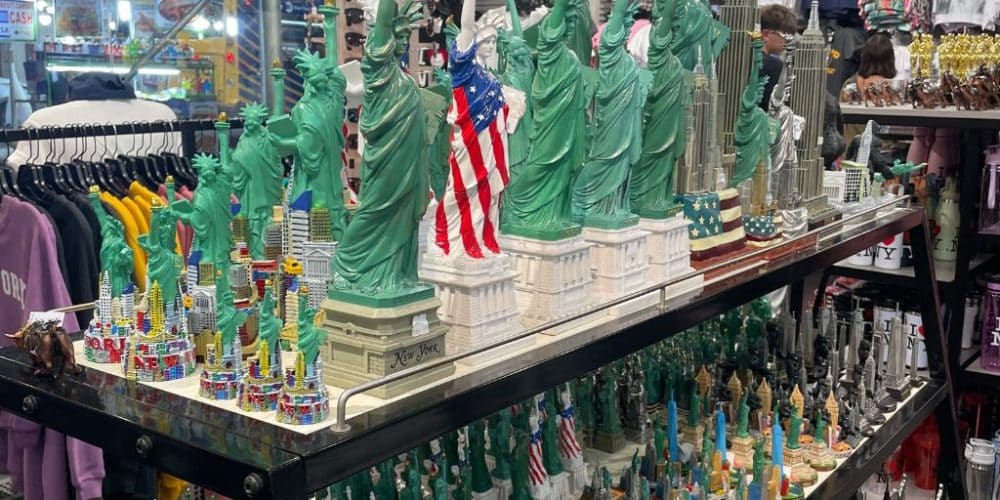 Souvenir shop display featuring various miniature Statue of Liberty replicas and New York City landmarks, emphasizing affordable keepsakes for tourists.