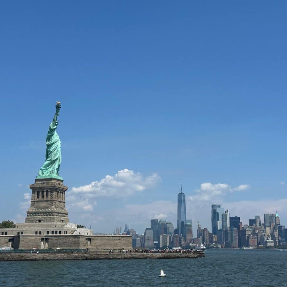 Statue of Liberty with NYC skyline in the background, symbolizing iconic New York City attractions and ferry experiences to Liberty Island.