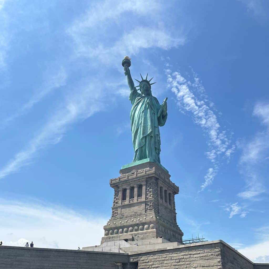 Statue of Liberty towering over Liberty Island under a clear blue sky, symbolizing freedom and a popular tourist attraction in New York City.