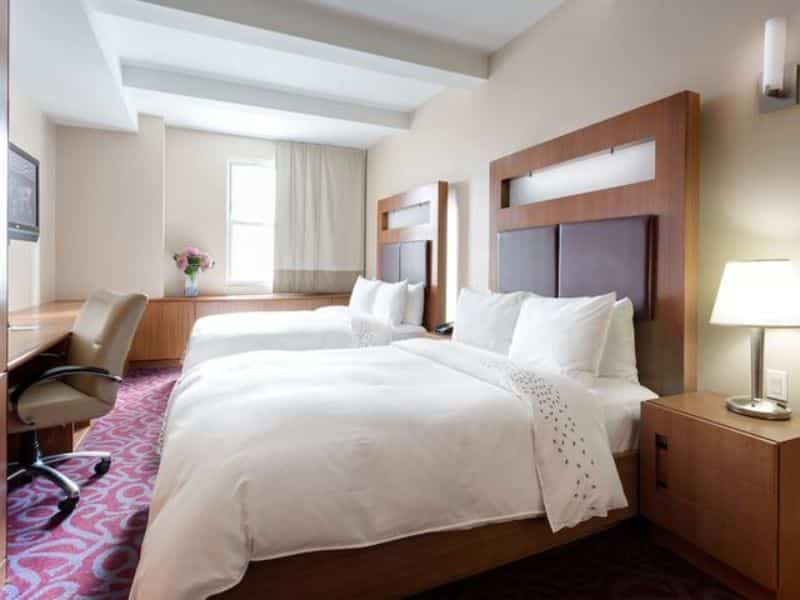 Hotel 57 guest room with two beds, modern decor, desk area, and natural light, featuring amenities for comfort and convenience.