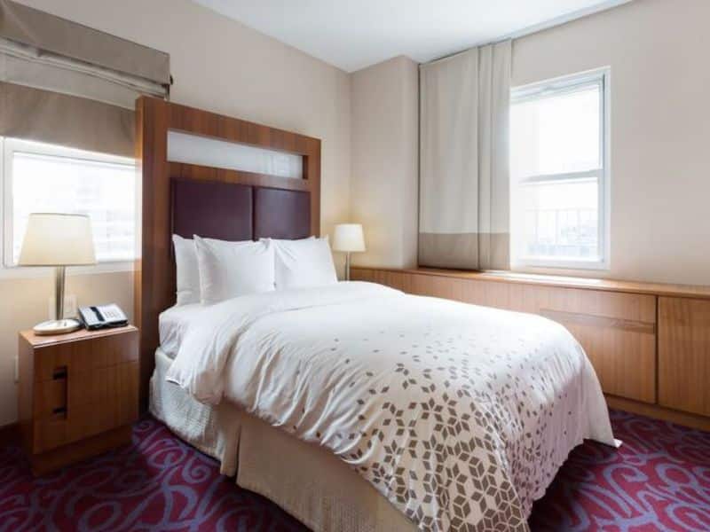 Modern hotel room at Hotel 57 featuring a queen bed, bedside lamp, and window, emphasizing comfort and convenience for travelers in Midtown Manhattan.