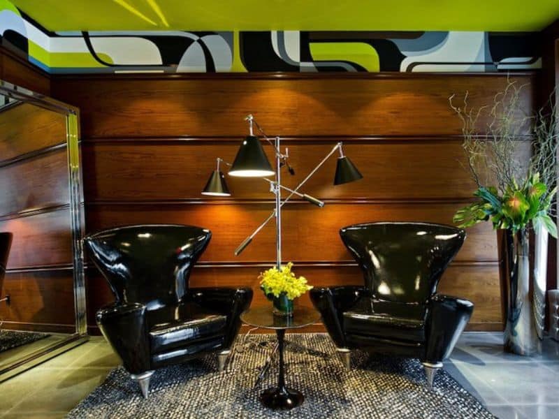 Modern lobby seating area with two black chairs, stylish floor lamp, and decorative plants, reflecting the contemporary design of Moderne Hotel in New York City.
