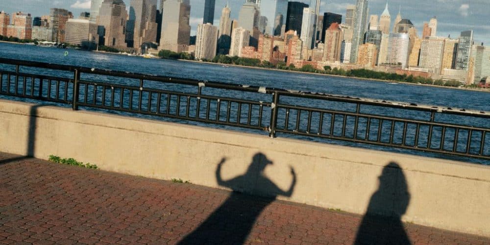 Shadows of two friends posing playfully in front of the New York City skyline, capturing a moment of spontaneity and joy during their travel adventure.