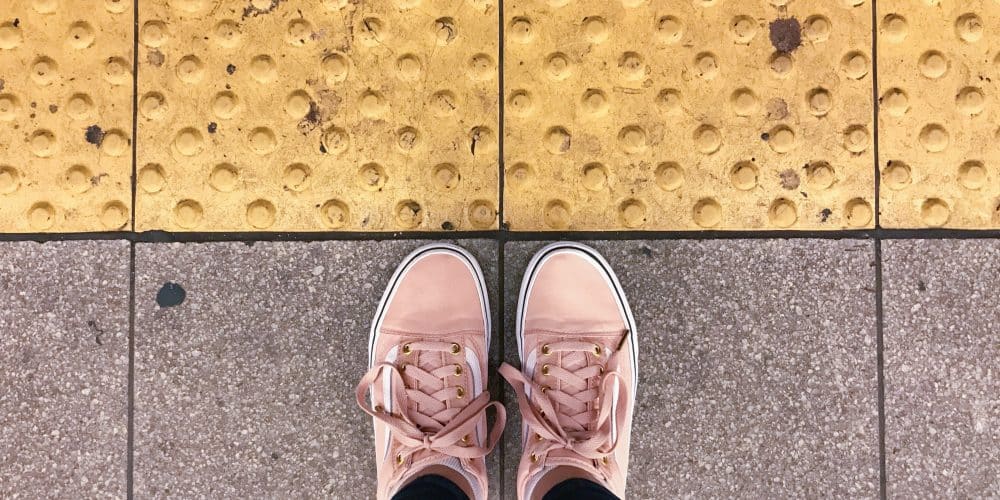 Comfortable pink sneakers on textured pavement, emphasizing the importance of walkable footwear for summer trips in NYC.