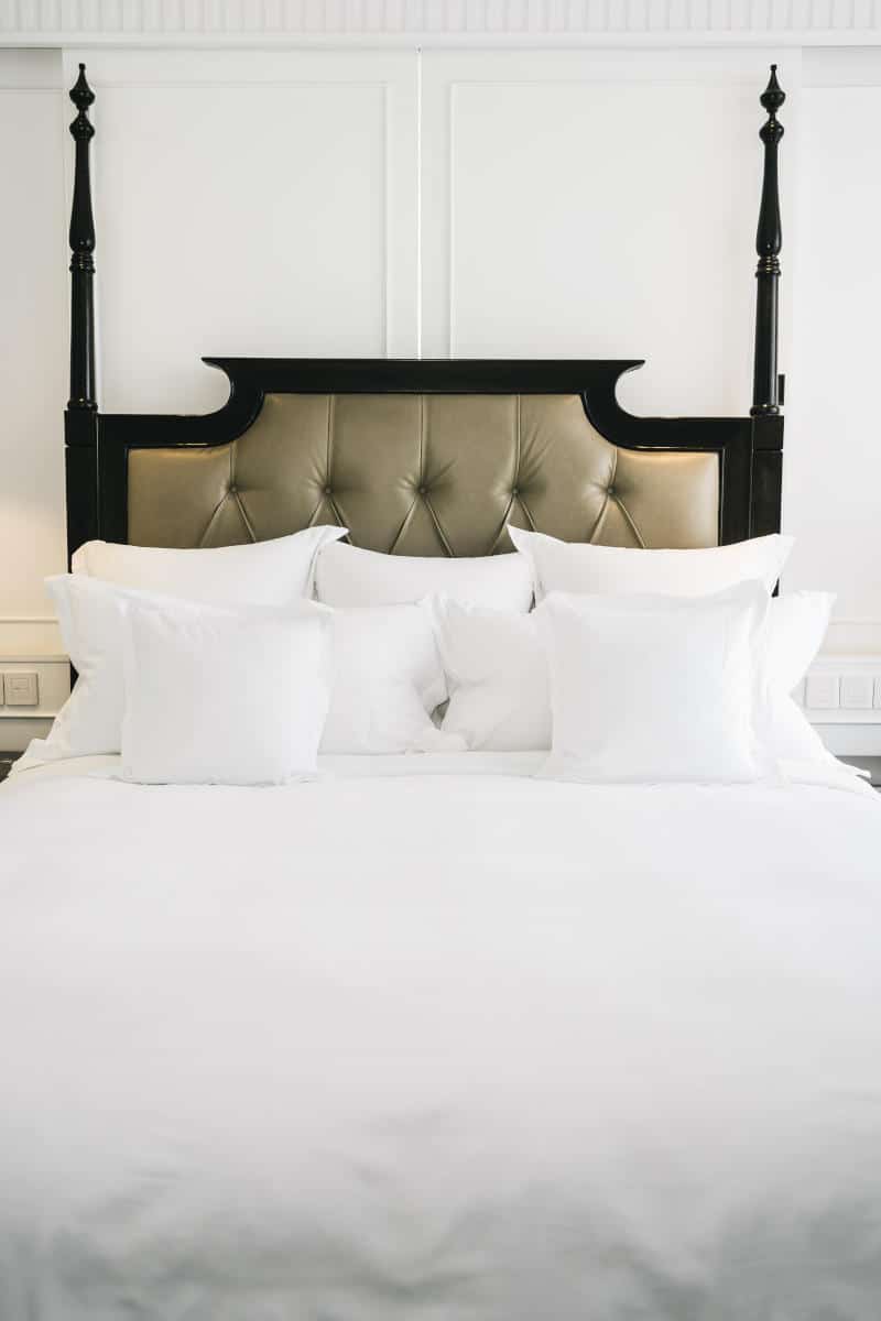 Elegant hotel bed with plush white pillows and a stylish headboard, reflecting boutique hotel luxury accommodations in New York City.