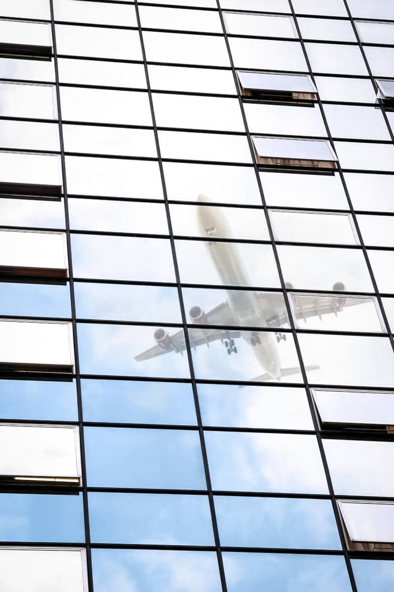 Reflection of an airplane in the glass facade of a hotel, highlighting proximity to JFK Airport, relevant for travelers seeking nearby accommodations in New York City.