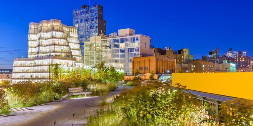 Elevated view of the High Line park featuring modern architecture, lush landscaping, and urban skyline at dusk, highlighting the blend of art and nature in New York City.