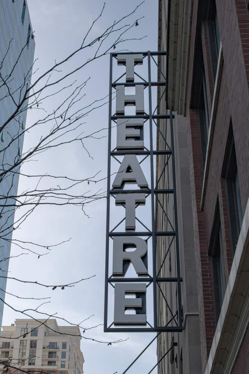 Theater sign prominently displayed against a city backdrop, representing New York City's vibrant entertainment scene and the Theater District.