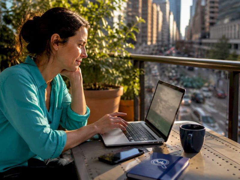 Woman comparing hotel prices on laptop at kitchen table