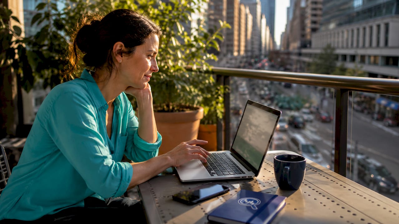 Woman comparing hotel prices on laptop at kitchen table