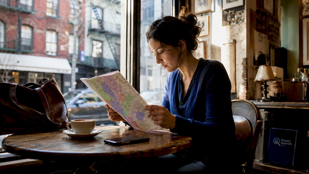 Traveler studying NYC hotel zones map at café