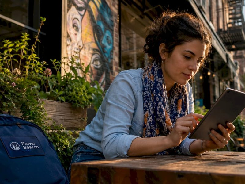 Woman using tablet at outdoor NYC caf&eacute; to plan trip