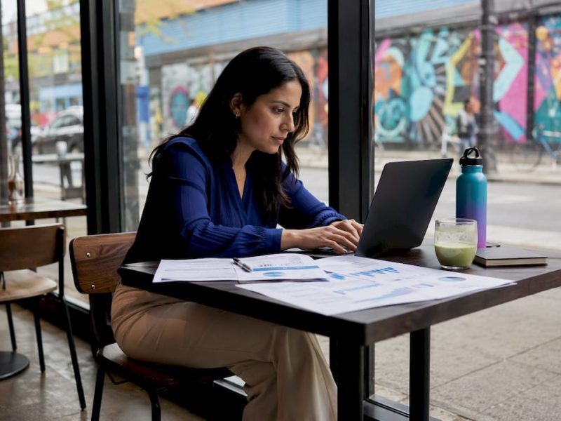 Woman at NYC café working on booking commission analysis